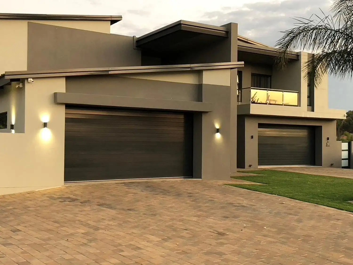 Fluted aluminium sectional garage doors in dark grey on a modern South African home with double and single garage