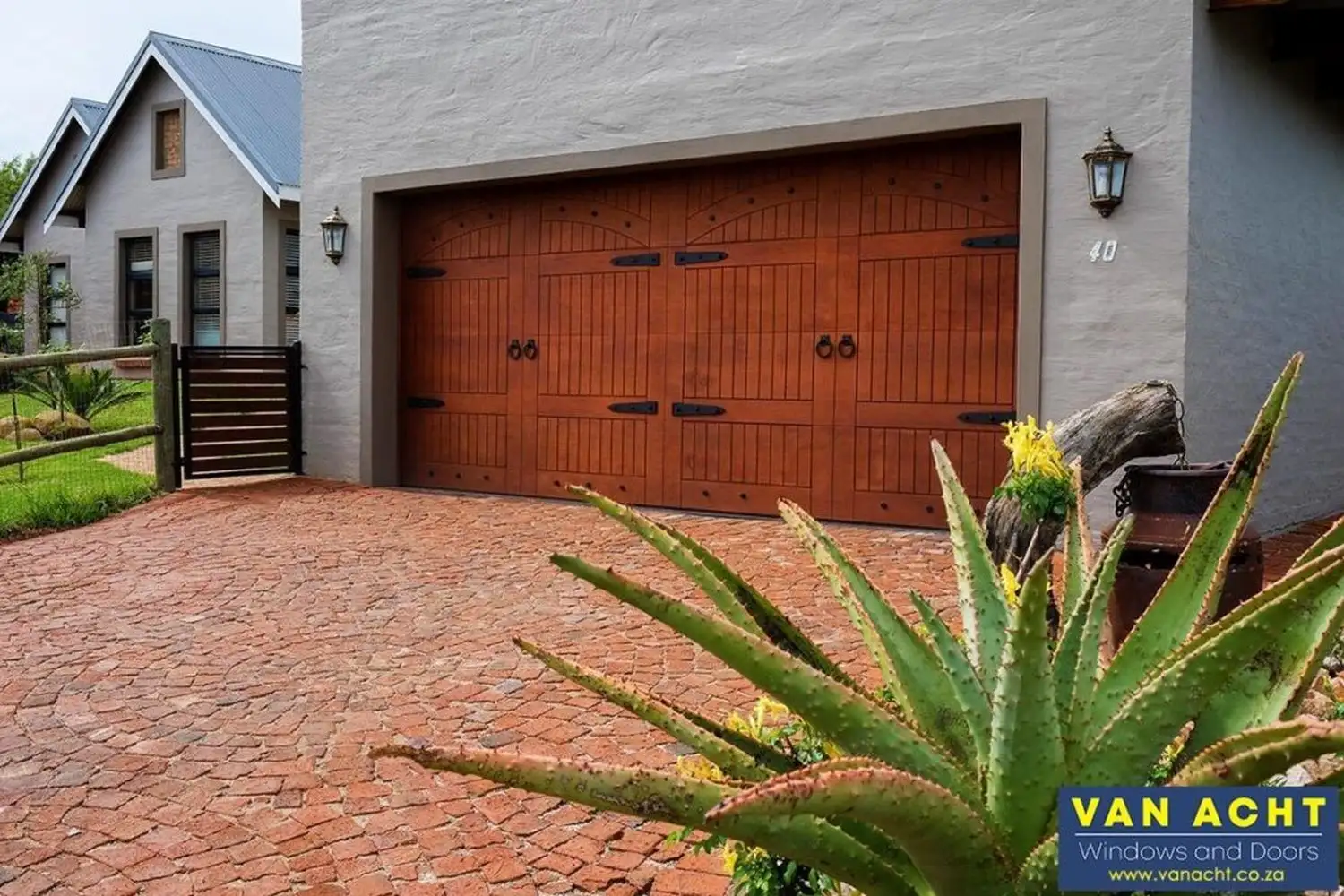 van acht wooden garage door marine ply rustic arched panel ironwork Van Acht wooden garage door in marine ply with rustic arched panel design and decorative ironwork hardware on a cottage-style South African home