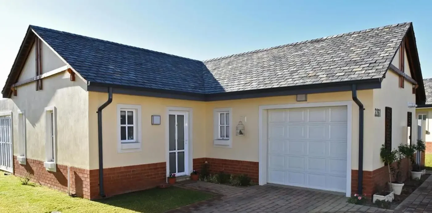 van acht aluminium zinc finish white panelled garage door slate roof home White panelled aluminium garage door with a zinc finish, on a traditional home with a slate-tile roof and red brick base course.